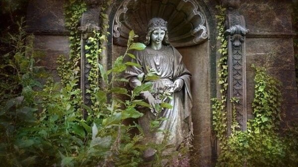 An der Friedhofsmauer, von Efeu umrankt, steht ein Engel, schön gekleidet, und schaut auf die Verstorbenen, deren Seelen in der Ewigkeit sich befinden