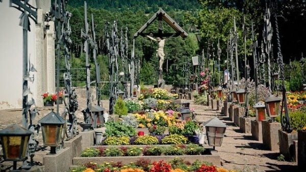 Ein Kirchhof mit Gräbern und vielen Kreuzen aus Eisen; in der Mitte im Hintergrund ein hölzernes großes Kruzifix; dies erinnert uns an Tod und Gericht