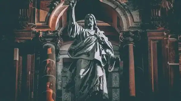 Jesus Christus der Auferstandene steht majestätisch unter einem mächtigen Steinbogen, die rechte Hand erhoben
