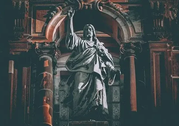 Jesus Christus der Auferstandene steht majestätisch unter einem mächtigen Steinbogen, die rechte Hand erhoben